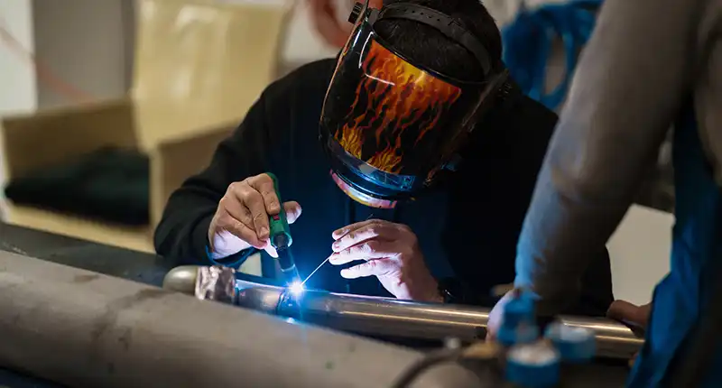 A professional shot of a finished, high-quality weld bead (preferably a TIG weld) on a fabricated metal product.
