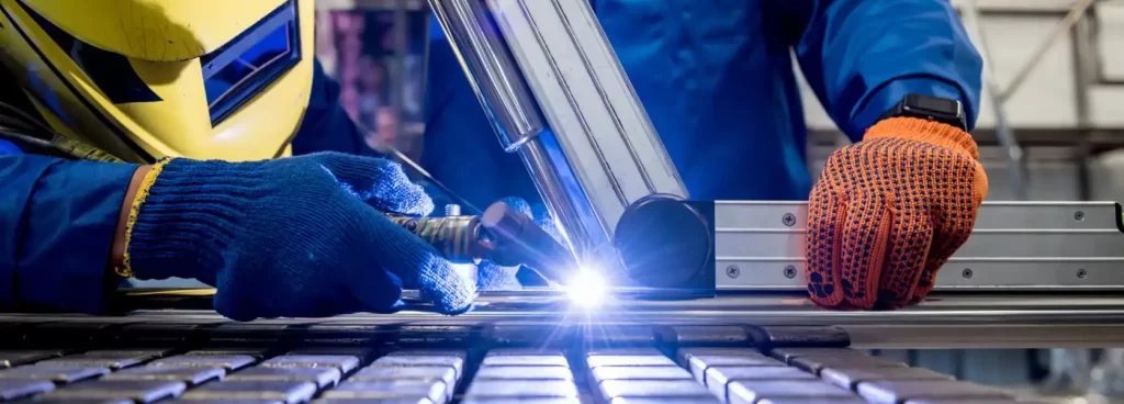 A team of engineers in Dubai reviewing blueprints with a fabricated steel structure in the background. Represents expertise and collaboration.